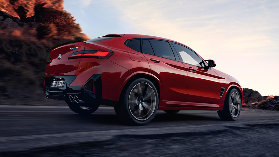 BMW X4 M F98 LCI Renovación 2021 Toronto Rot metalizado Vista de tres cuartos de la zaga circulando por una carretera