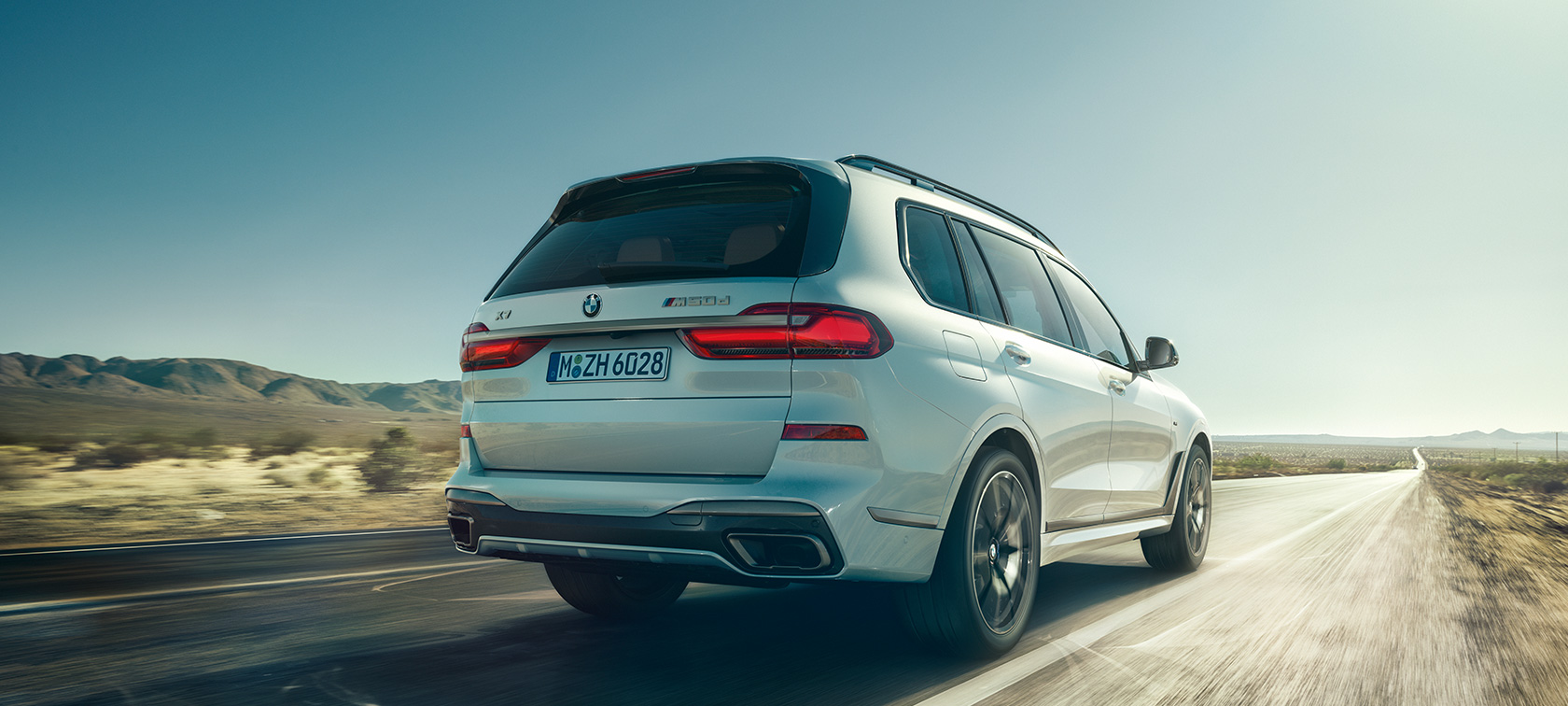 BMW X7 M50d in Mineral White, driving on an empty highway, rear view, G07, 2019